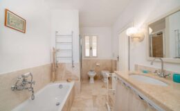 Modern bathroom featuring a spacious tub, elegant fixtures, a stylish vanity with a large mirror, and neutral-toned tiles, creating a bright and inviting atmosphere.