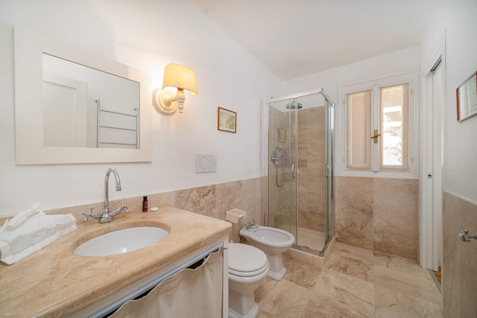 Modern bathroom featuring a glass shower, marble countertops, a stylish sink, and elegant lighting. The design includes neutral tones and a window for natural light. | Only on SopranoVillas