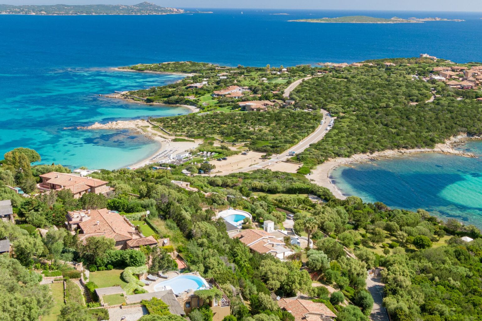 Aerial view of a coastal landscape featuring lush greenery, sandy beaches, and turquoise waters, showcasing a serene vacation destination with luxury homes and scenic shorelines. | Only on SopranoVillas