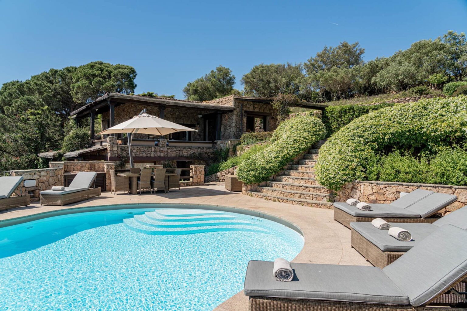 Luxury villa with a swimming pool, sun loungers, and landscaped gardens in a serene outdoor setting. Perfect for relaxation and leisure. | Only on SopranoVillas