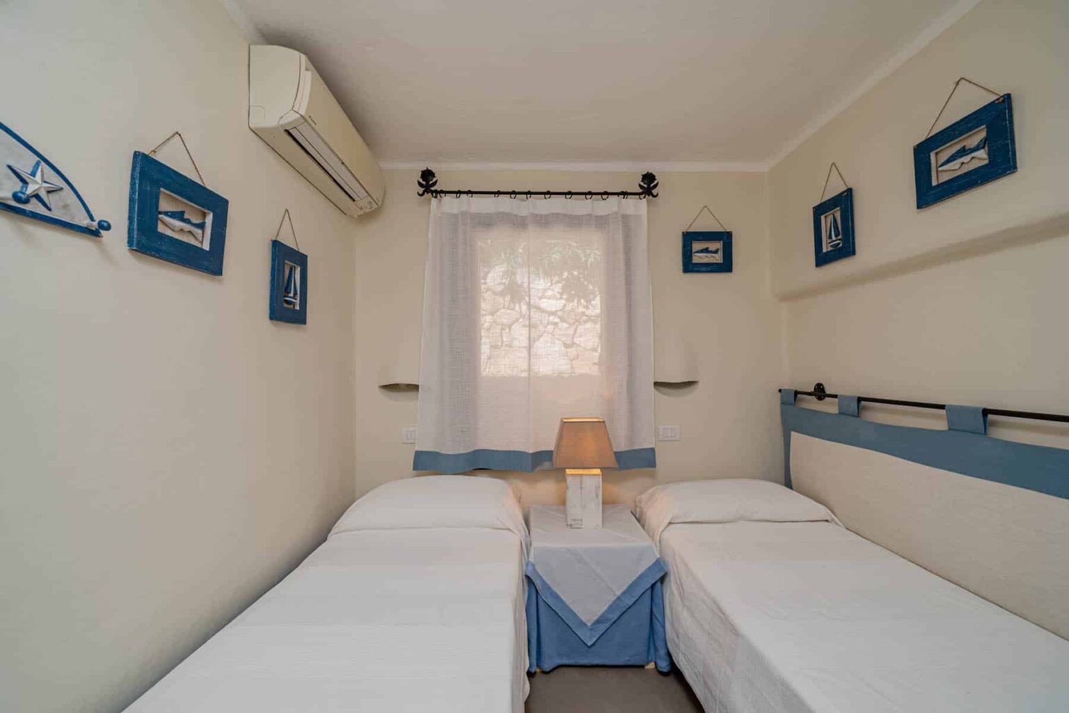 Cozy bedroom with two twin beds, blue accents, air conditioning, and decorative wall art, perfect for a relaxing stay. | Only on SopranoVillas