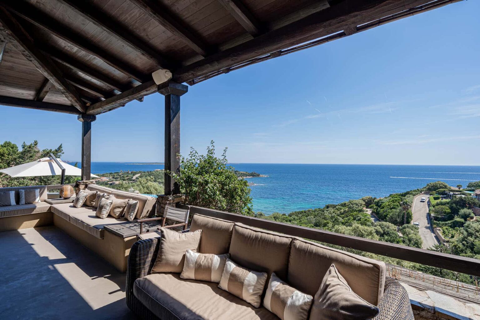 Cozy outdoor seating area with a panoramic view of the ocean and lush greenery, perfect for relaxation and enjoying the scenic landscape. | Only on SopranoVillas