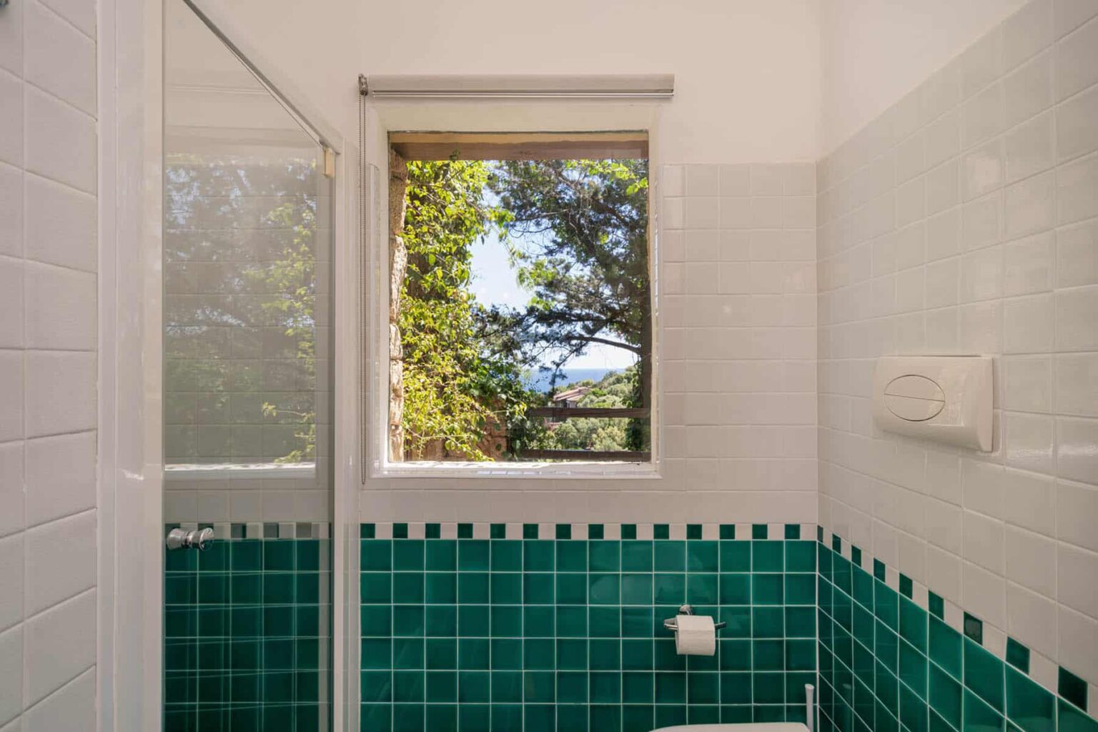 Bright bathroom featuring green tiled walls and a window overlooking lush greenery, providing natural light and a view of the outdoors. | Only on SopranoVillas