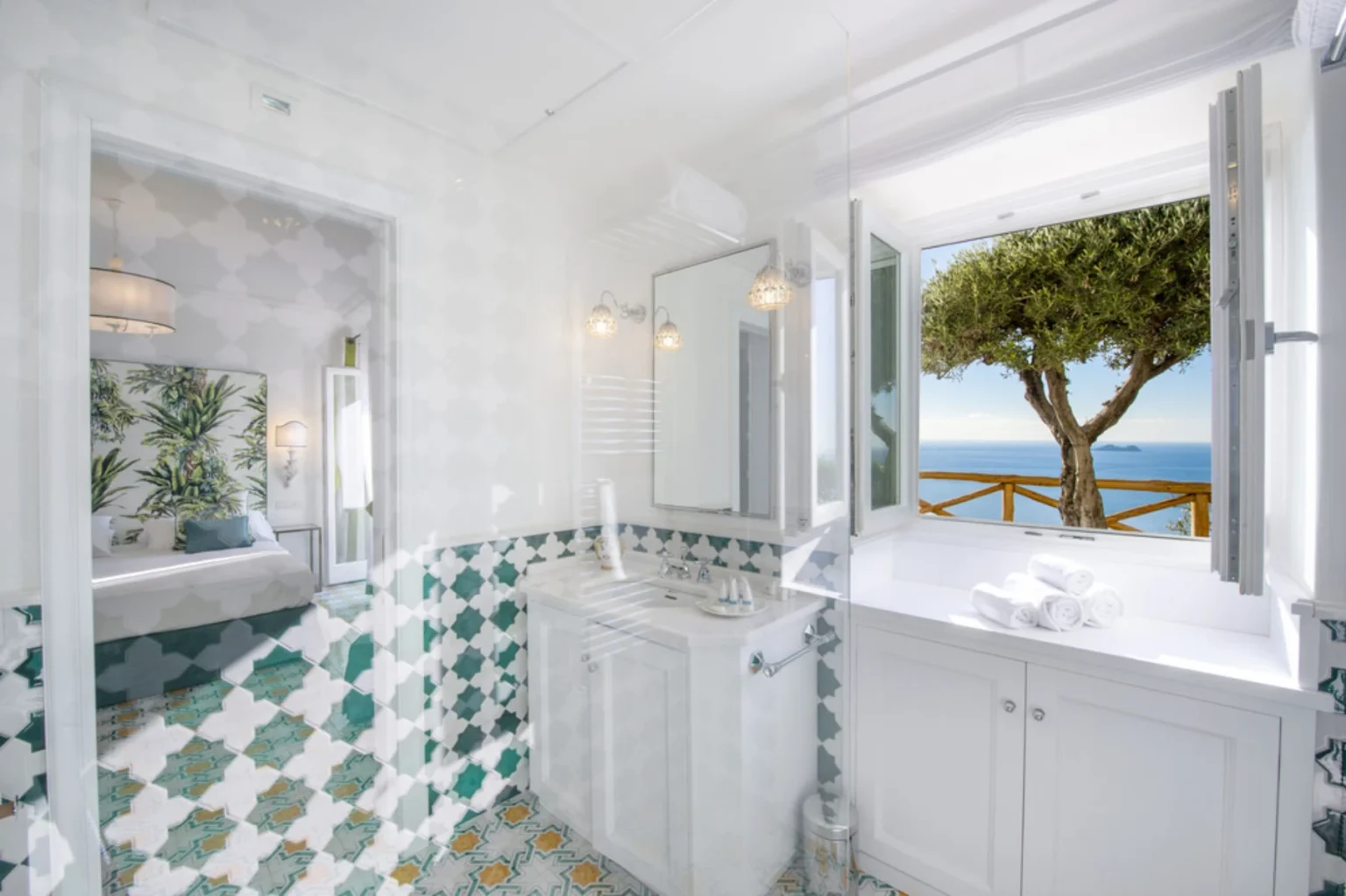 Luxurious bathroom featuring elegant tile work, modern fixtures, and a stunning ocean view through open windows. The space is bright and airy, with fresh towels neatly arranged on the counter. | Only on SopranoVillas