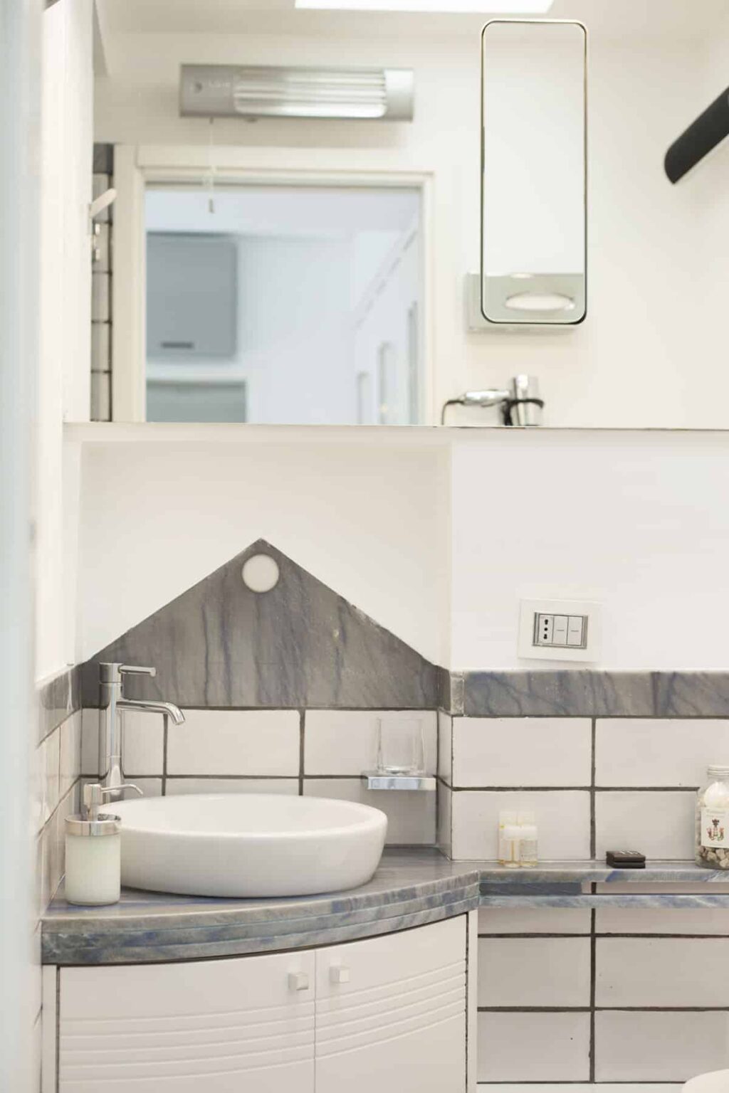 Modern bathroom interior featuring a sleek sink and contemporary wall design with gray tiles, complemented by minimalist fixtures and a neutral color palette. | Only on SopranoVillas