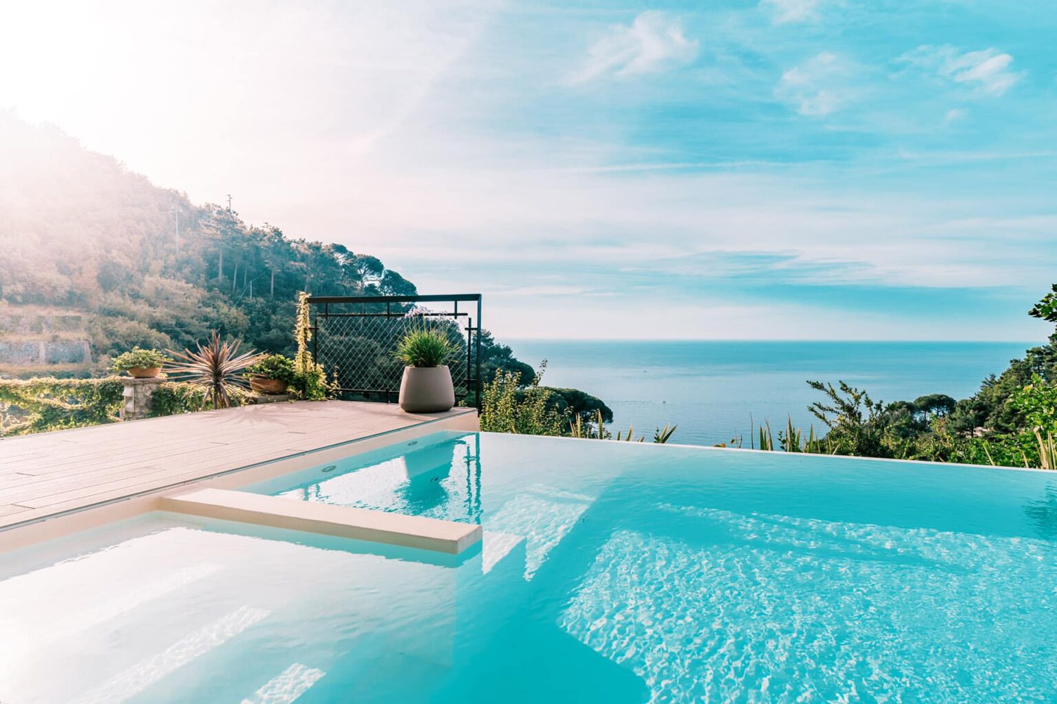 Luxury villa with an infinity pool overlooking a serene ocean landscape, surrounded by lush greenery and clear blue skies. Perfect for a relaxing getaway. | Only on SopranoVillas