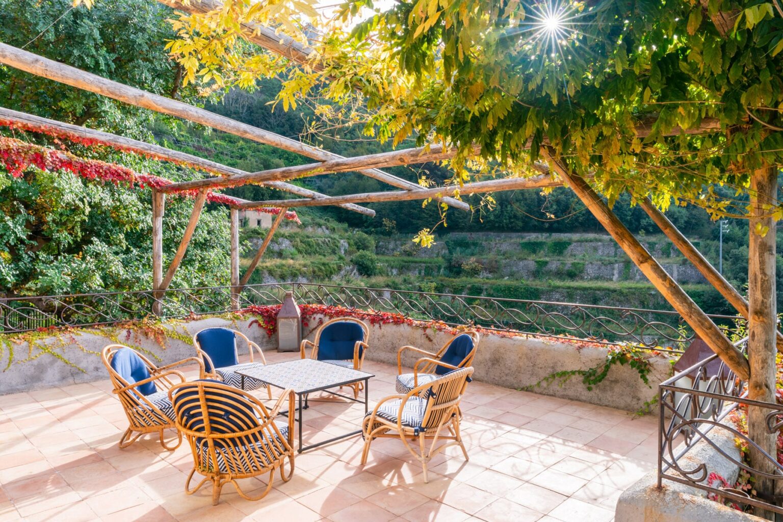 Cozy outdoor patio area with wicker furniture, surrounded by lush greenery and vines, ideal for relaxation and gatherings. | Only on SopranoVillas