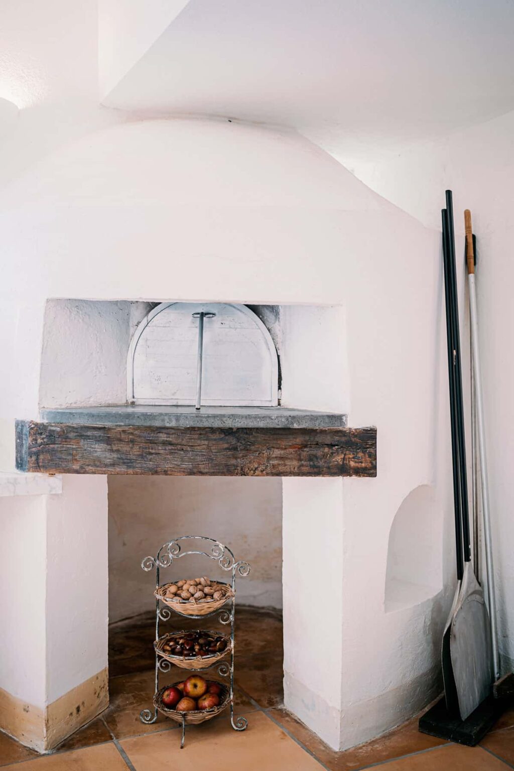 Traditional brick pizza oven with a wooden mantel, showcasing a white interior and a rounded entrance, ideal for cooking authentic pizzas. | Only on SopranoVillas