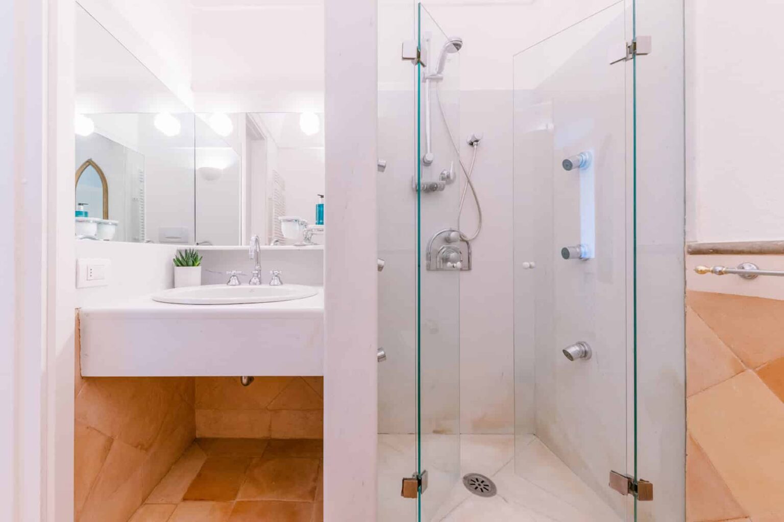 Modern bathroom with a glass shower enclosure, sleek white sink, and contemporary fixtures. Natural light illuminates the space, highlighting the neutral color palette and minimalist design. | Only on SopranoVillas