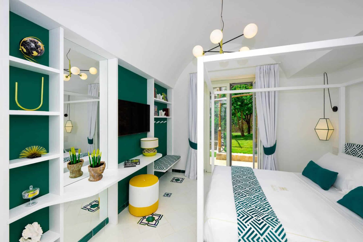 Modern bedroom interior featuring a four-poster bed, vibrant teal walls, stylish lighting fixtures, and a cozy seating area with garden views. Decor includes decorative plants and contemporary furniture, creating a chic and inviting atmosphere. | Only on SopranoVillas