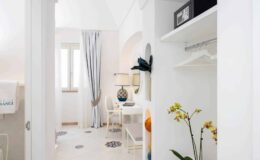 Bright and modern interior of a stylish room featuring a small dining area, decorative lamp, and a touch of greenery, showcasing a minimalist design with white walls and elegant furnishings.