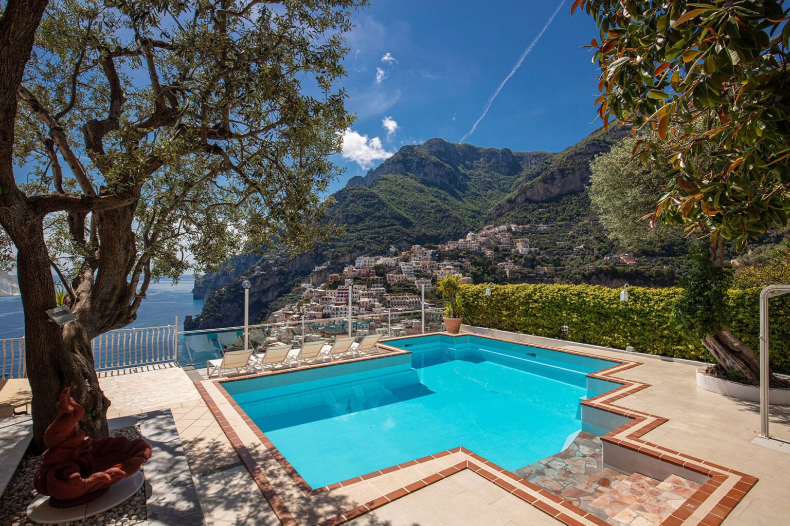 Luxurious outdoor pool with stunning mountain and sea views, surrounded by lush greenery and a sun terrace, ideal for relaxation and leisure in a coastal villa setting. | Only on SopranoVillas