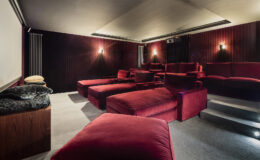 Home theater interior featuring plush red seating, a large projection screen, and ambient lighting for a cozy movie-watching experience.