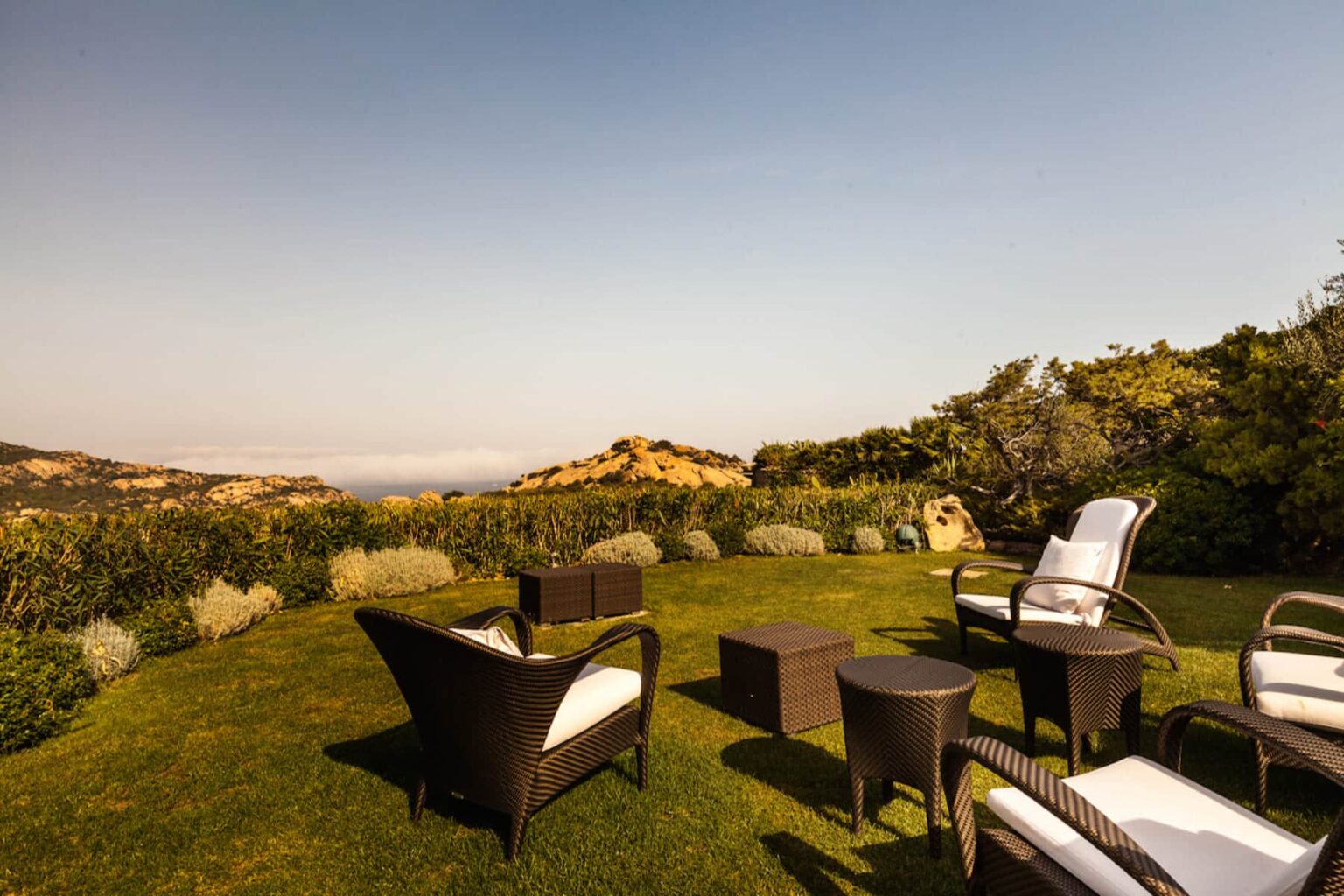 Outdoor seating area with stylish furniture overlooking a scenic landscape, featuring lush greenery and distant hills under a clear sky. Perfect for relaxation and enjoying nature. | Only on SopranoVillas