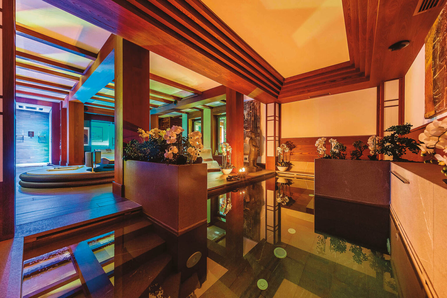 Luxurious spa interior featuring wooden beams, tranquil water features, and vibrant lighting, creating a serene atmosphere for relaxation and wellness. | Only on SopranoVillas