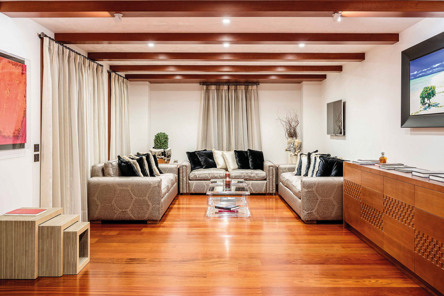 Modern living room with wooden beams, stylish sofas, and hardwood flooring, featuring decorative art and elegant curtains for a cozy ambiance. | Only on SopranoVillas