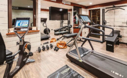 Home gym with modern exercise equipment including a treadmill, stationary bike, and free weights, featuring a stylish interior and ample natural light.