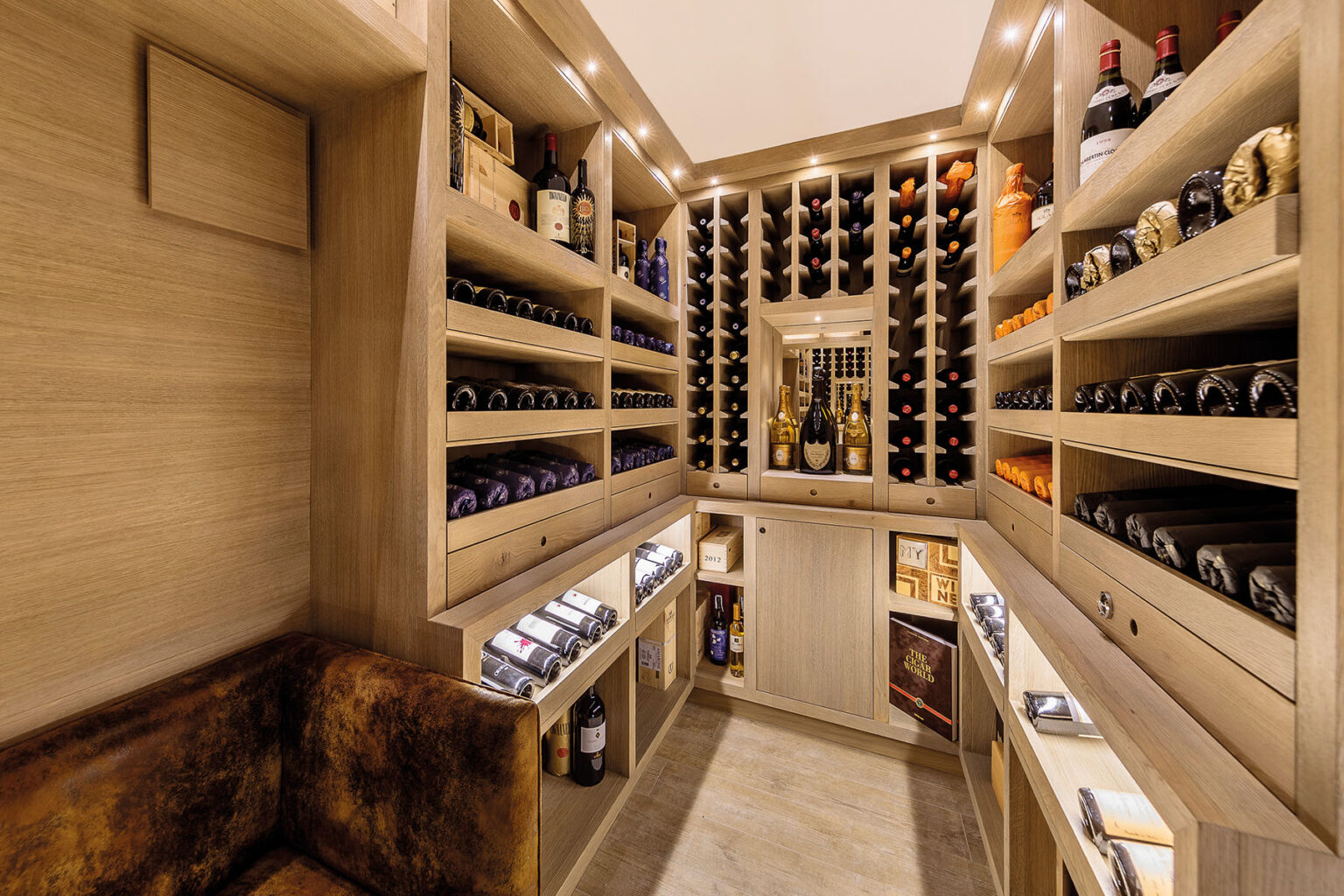 Luxury wine cellar featuring custom wooden shelving, a cozy leather seating area, and a variety of wine bottles displayed prominently. The design includes ambient lighting and organized storage for both bottles and accessories, creating an elegant and functional space for wine enthusiasts. | Only on SopranoVillas