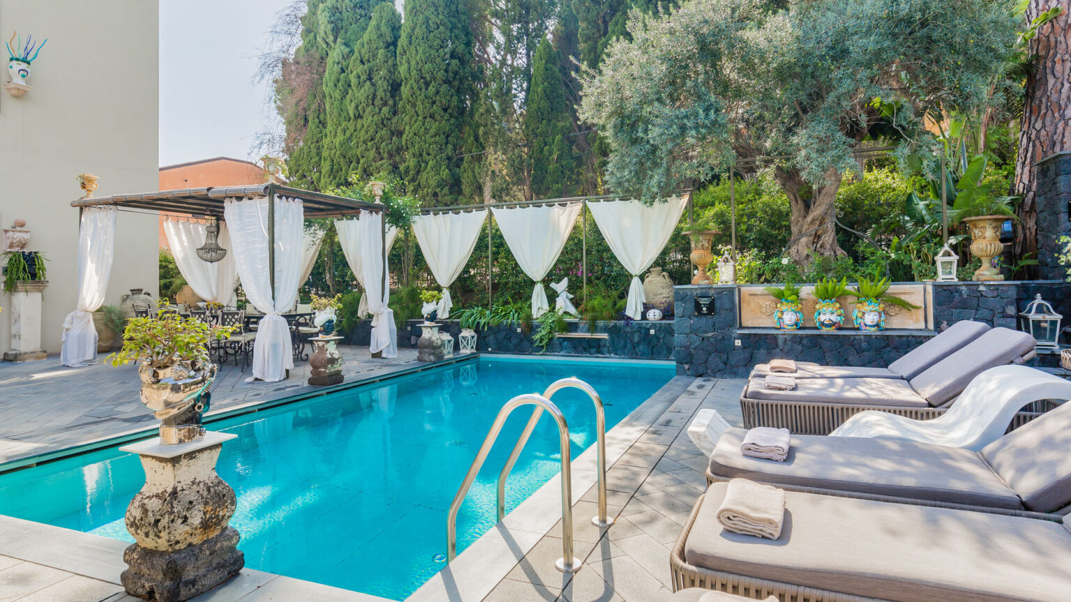 Luxurious outdoor pool area featuring comfortable lounge chairs, elegant cabanas, and lush greenery, perfect for relaxation and leisure. | Only on SopranoVillas