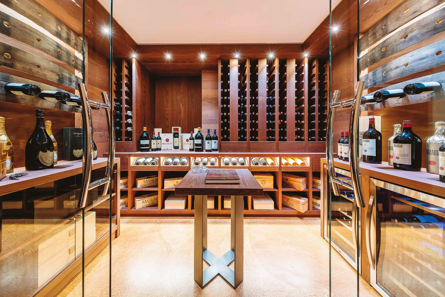 Elegant wine cellar featuring wooden shelves filled with a variety of wines, a central tasting table, and modern glass doors, creating a sophisticated ambiance for wine enthusiasts. | Only on SopranoVillas