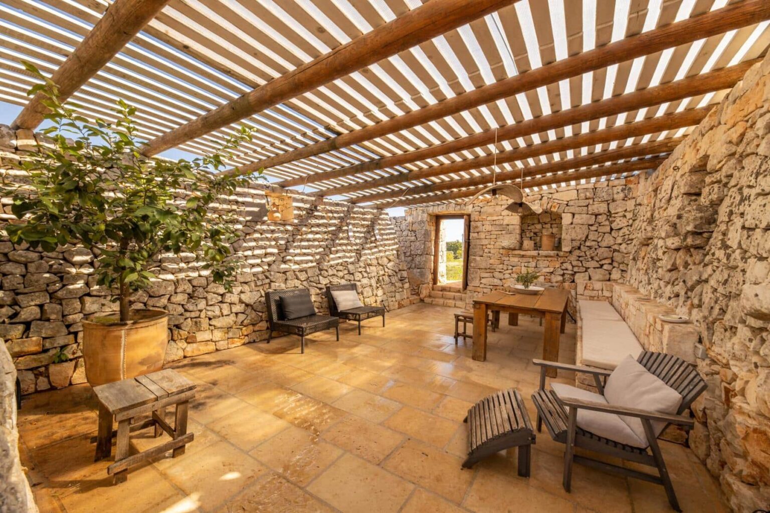 Cozy interior of a stone cottage featuring wooden beams, natural light, and rustic furniture, ideal for relaxation and gatherings. | Only on SopranoVillas