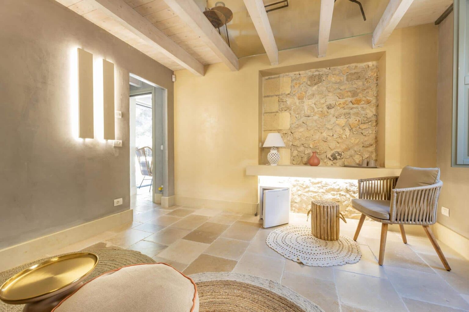 Modern living room with stone accent wall, stylish furniture, and natural lighting. Features include a comfortable armchair, minimalist decor, and elegant lighting fixtures. Ideal for contemporary home design inspiration. | Only on SopranoVillas