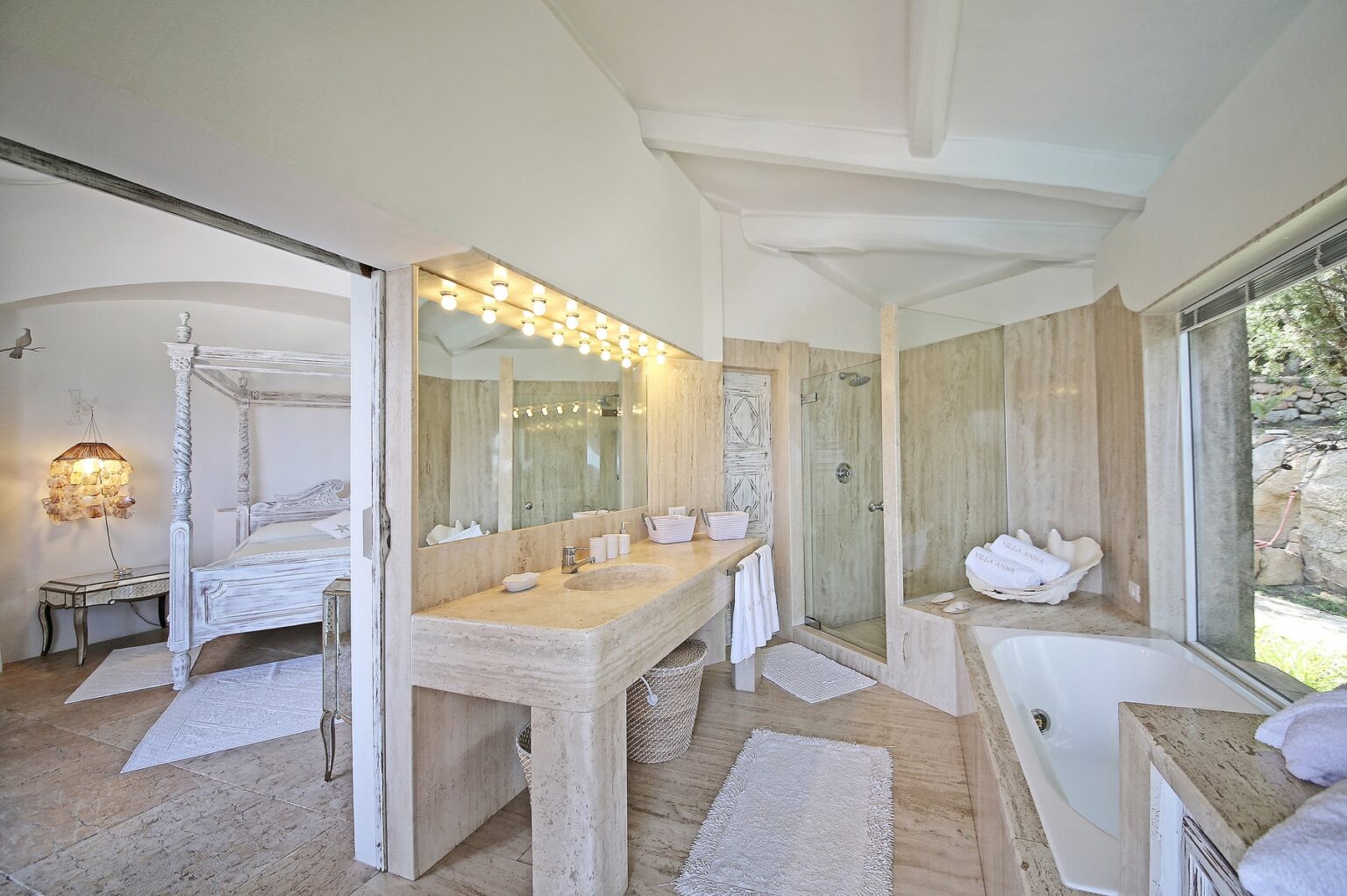 Spacious modern bathroom featuring a double vanity, glass shower, and freestanding tub, with natural light streaming in from large windows and neutral decor for a serene atmosphere. | Only on SopranoVillas