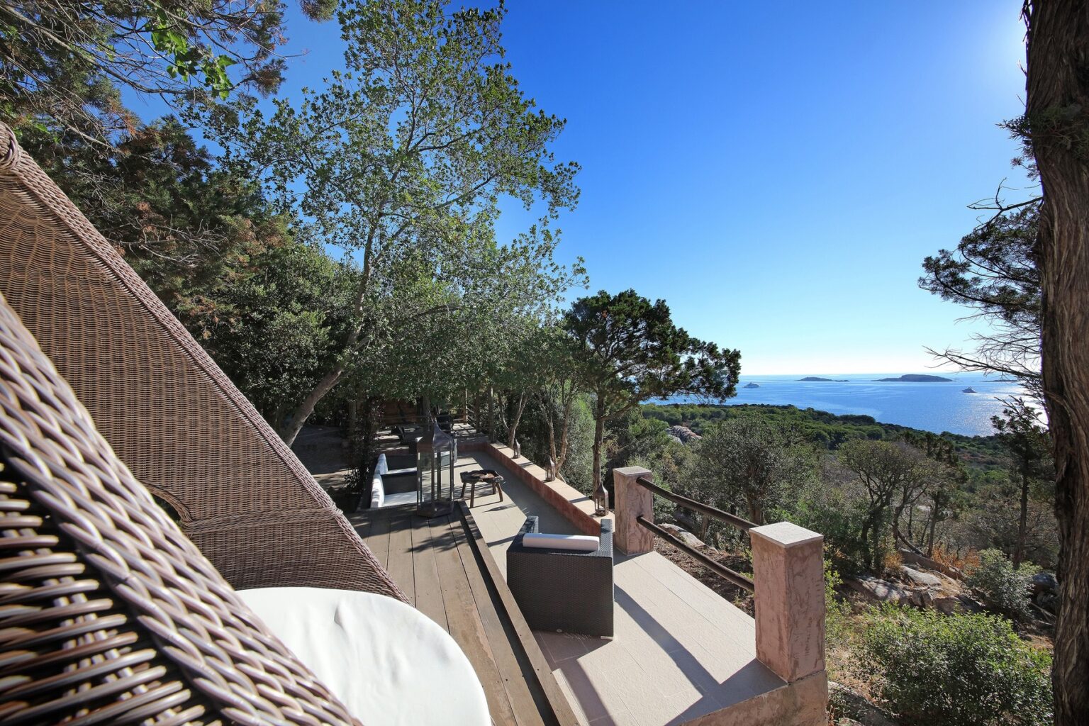 Scenic view from a terrace overlooking the ocean, surrounded by trees and outdoor seating, ideal for relaxation and enjoying nature. | Only on SopranoVillas