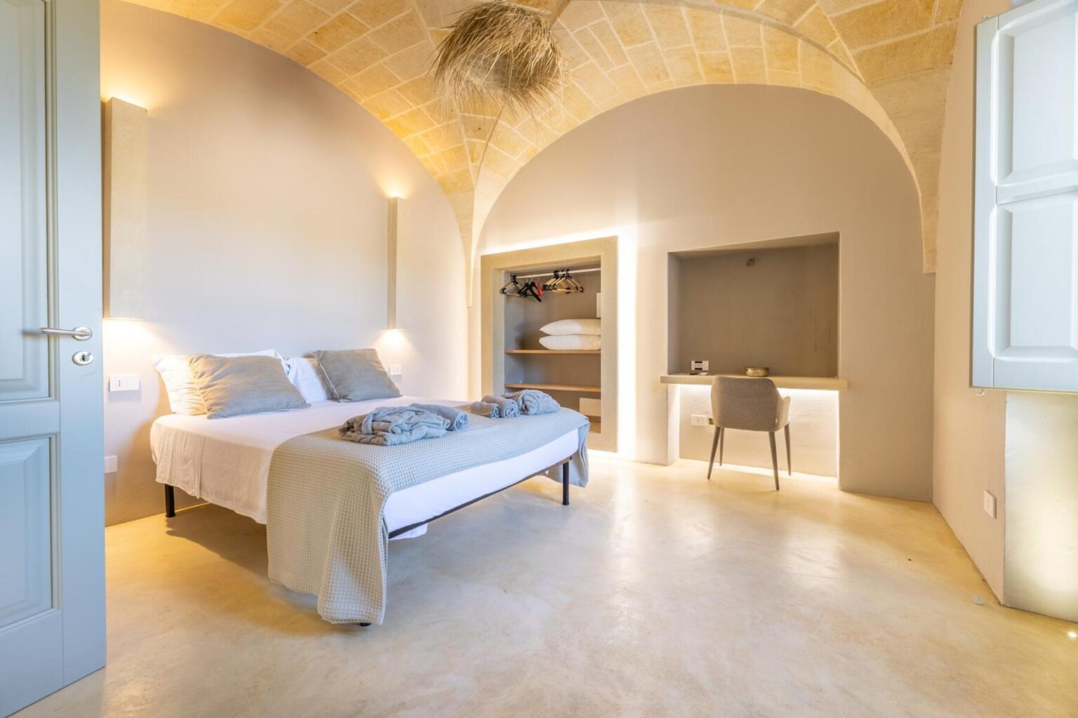 Modern bedroom interior featuring a comfortable bed, stylish decor, and a cozy workspace. The room has a vaulted ceiling, soft lighting, and minimalist furnishings, creating a serene atmosphere ideal for relaxation or work. | Only on SopranoVillas