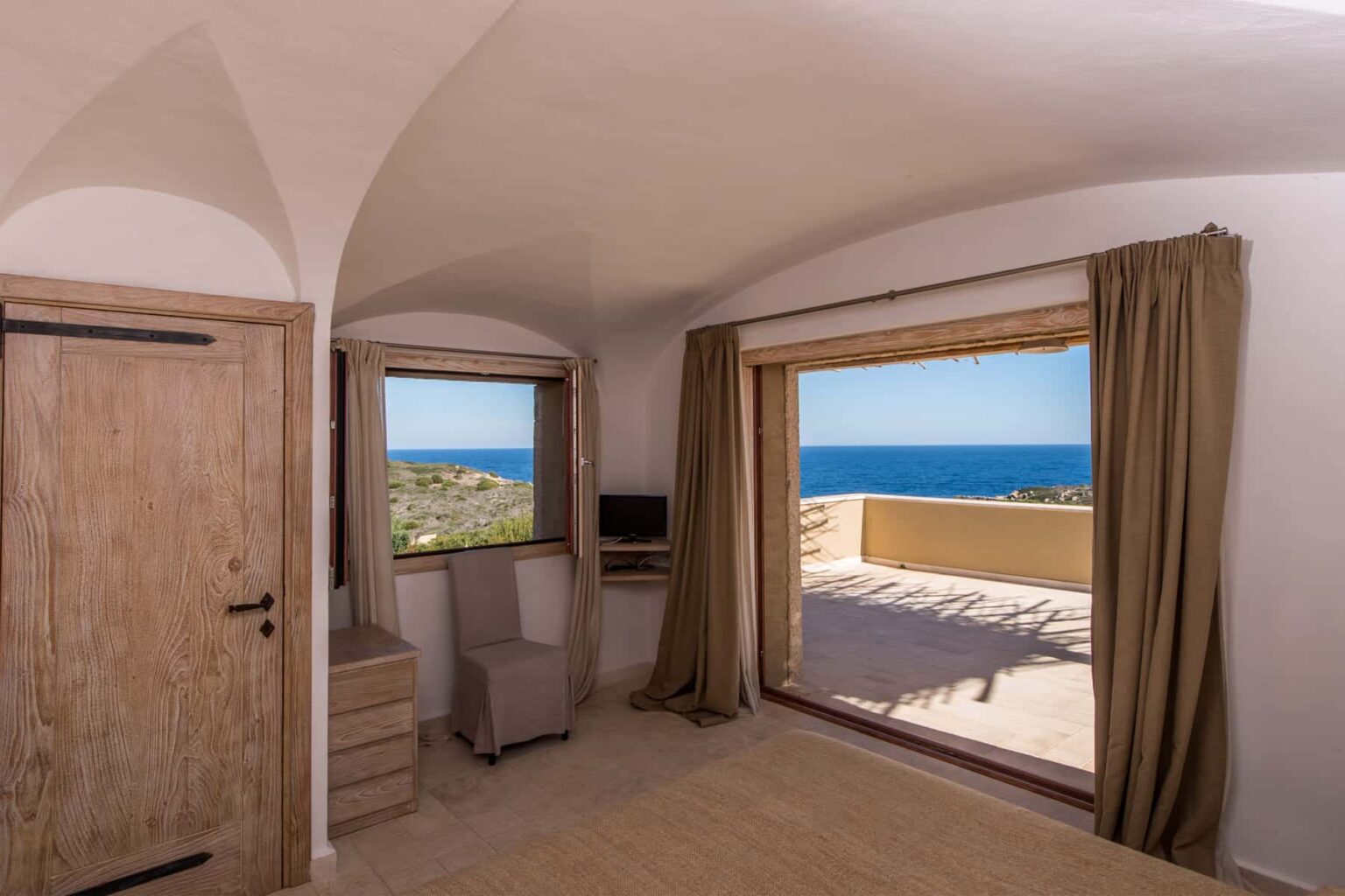 Cozy bedroom with modern furnishings, large windows offering a stunning ocean view, and a private terrace. Ideal for relaxation and enjoying scenic coastal landscapes. | Only on SopranoVillas