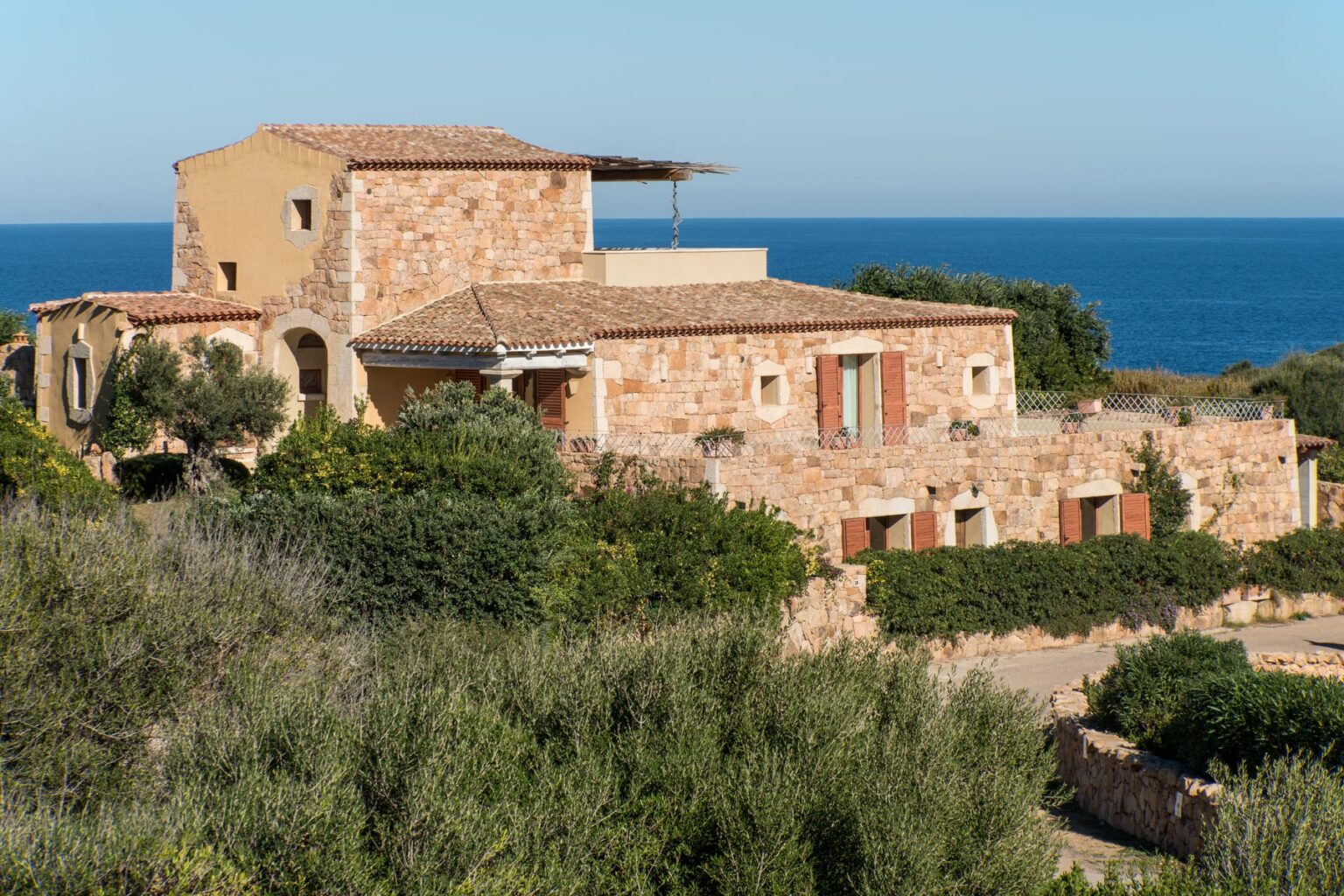 Cozy stone villa overlooking the ocean, surrounded by lush greenery and shrubs, ideal for a peaceful retreat. | Only on SopranoVillas