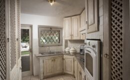 Cozy kitchen with light wood cabinets, granite countertops, and a window featuring decorative lattice. The layout is compact, showcasing modern appliances and a warm, inviting atmosphere.