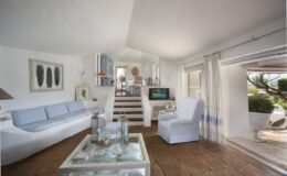 Bright and airy living room featuring a white sofa, stylish decor, and large windows that open to a scenic outdoor space. The room is designed with a modern aesthetic, showcasing natural light and a welcoming atmosphere.