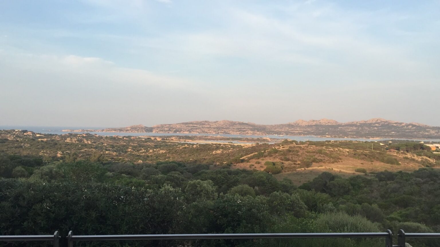 Scenic landscape view featuring rolling hills and distant mountains under a blue sky, with lush greenery in the foreground. Ideal for nature enthusiasts and travel content. | Only on SopranoVillas