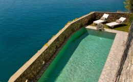 Luxury villa with a private pool overlooking the serene waters of Italy, featuring sun loungers for relaxation and stunning views. Ideal for a premium vacation rental experience.