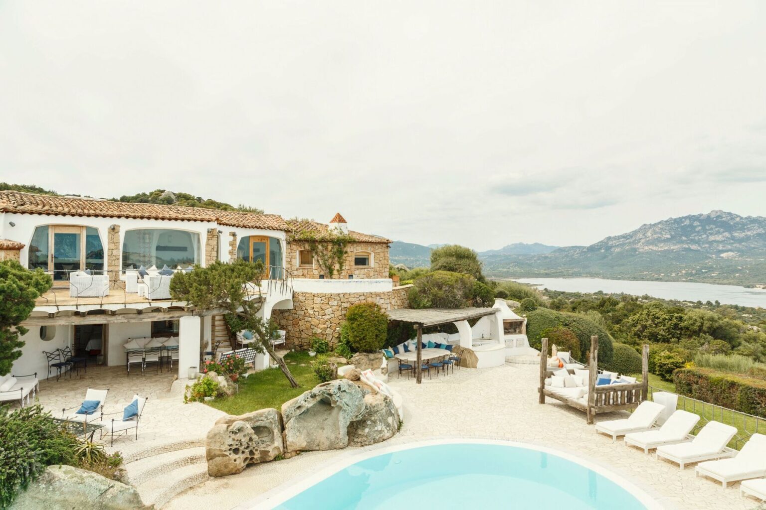 Stunning villa with a pool overlooking scenic hills and water, featuring outdoor seating and lush greenery, ideal for luxury vacations. | Only on SopranoVillas
