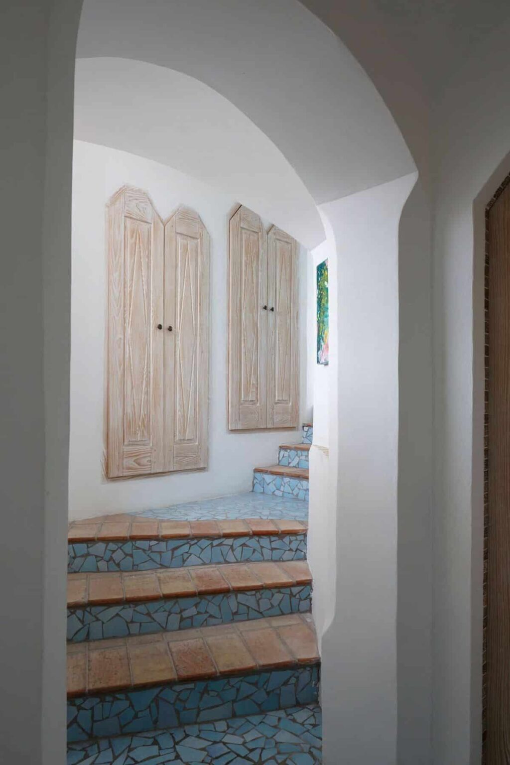 Interior view of a stylish hallway featuring wooden cabinets, colorful tiled steps, and a bright window, showcasing a modern yet inviting design. | Only on SopranoVillas