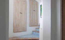 Interior view of a stylish hallway featuring wooden cabinets, colorful tiled steps, and a bright window, showcasing a modern yet inviting design.