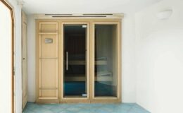 Modern sauna with wooden accents and glass doors, featuring blue tiled flooring and a minimalist design, ideal for relaxation and wellness.