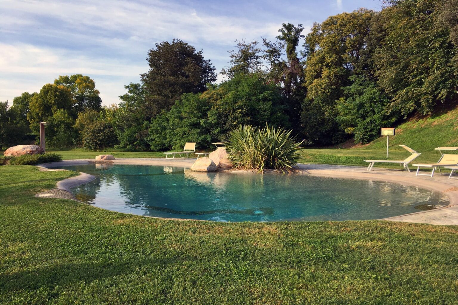 Serene outdoor swimming pool surrounded by lush greenery and comfortable lounge chairs, ideal for relaxation and leisure in a natural setting. | Only on SopranoVillas
