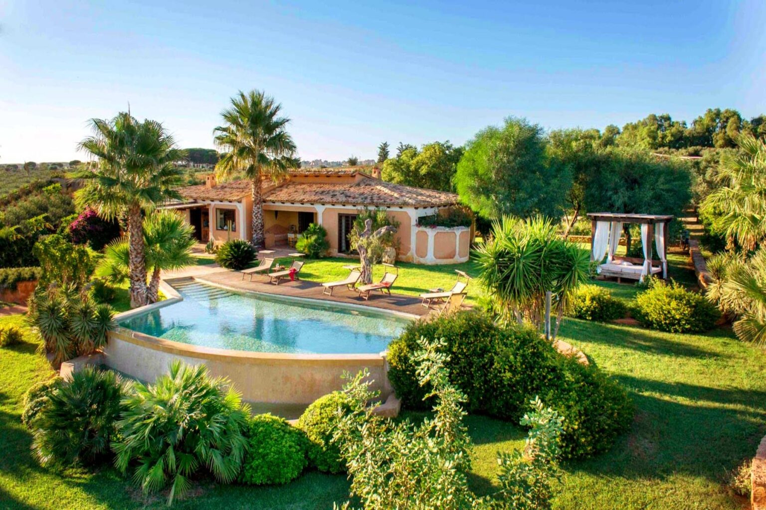 Luxurious villa with a swimming pool surrounded by lush greenery and palm trees, featuring a spacious outdoor area and scenic views. Ideal for relaxation and outdoor living. | Only on SopranoVillas