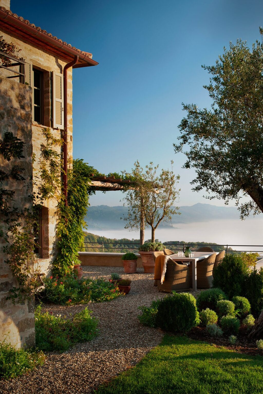 Scenic view from a rustic villa featuring lush greenery, a pergola, and mountains in the background, perfect for a tranquil getaway. | Only on SopranoVillas