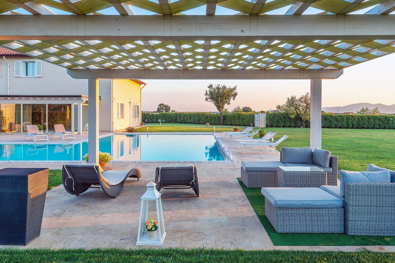 Luxury outdoor living space featuring a modern pergola, comfortable seating, and a pristine swimming pool surrounded by lush greenery. Ideal for relaxation and entertaining in a serene setting. | Only on SopranoVillas