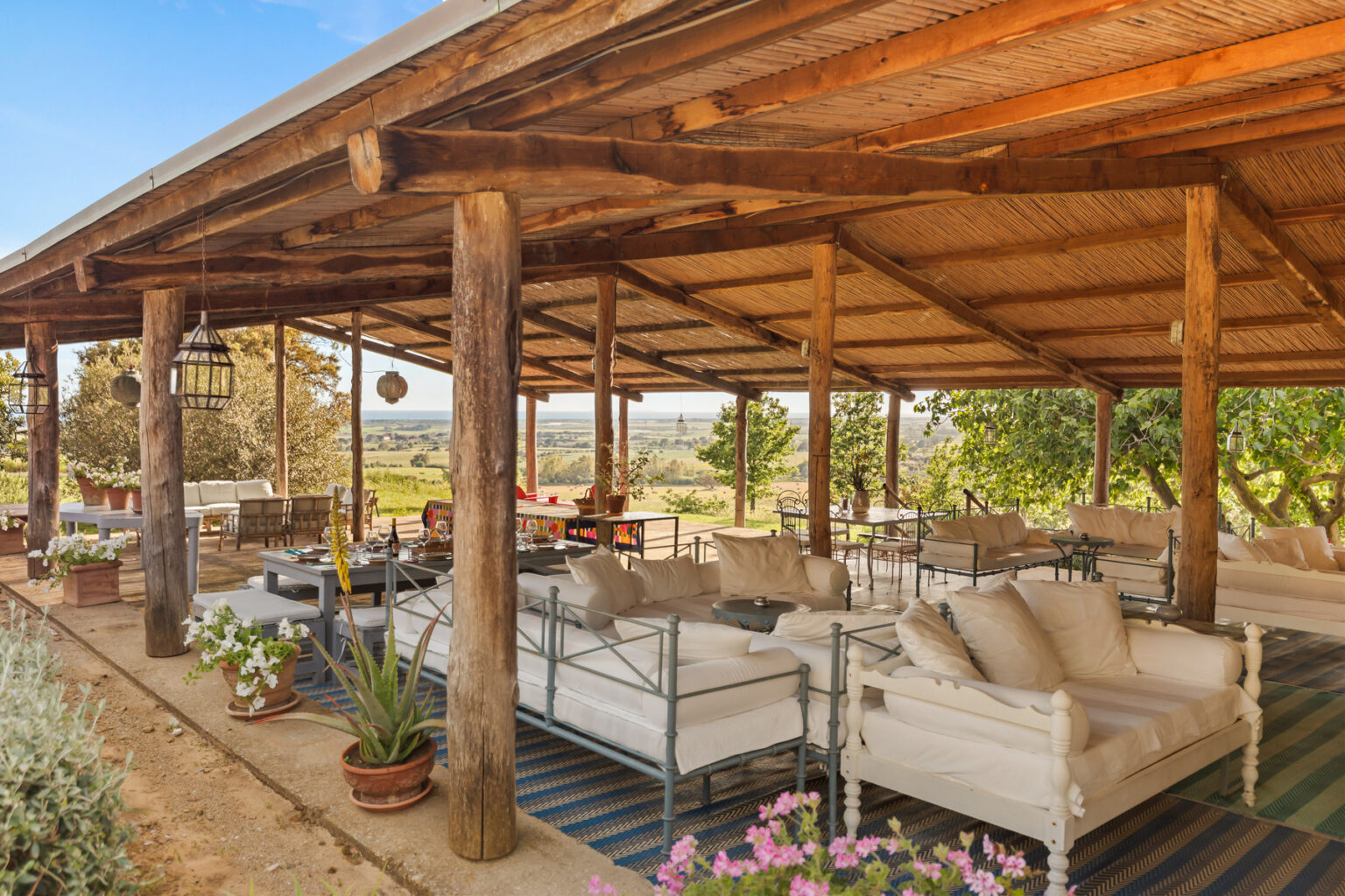 Spacious outdoor patio with rustic wooden beams, comfortable seating, and scenic views of the surrounding landscape, featuring potted plants and a relaxed atmosphere. | Only on SopranoVillas