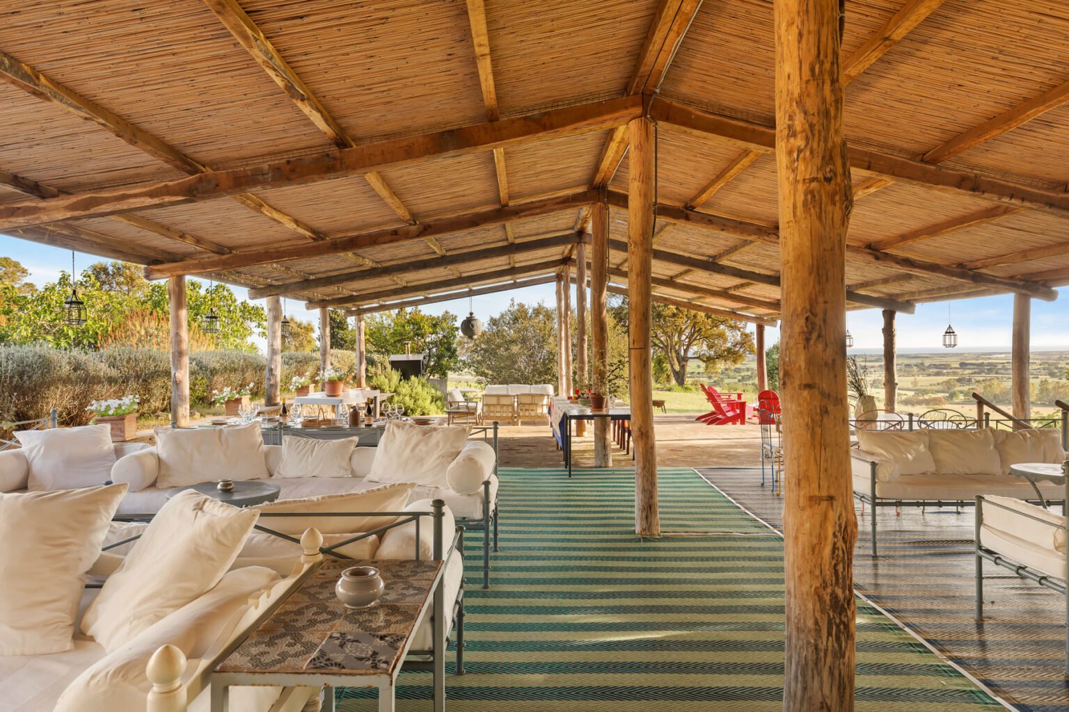 Spacious outdoor lounge area with wooden beams, comfortable seating, and a scenic view, perfect for relaxation and gatherings. | Only on SopranoVillas