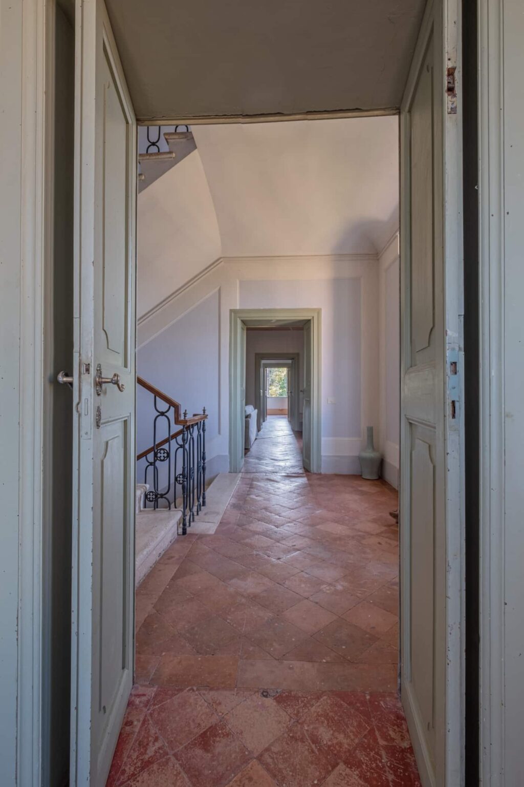 Interior view of a hallway with a staircase, featuring elegant doors and a tiled floor, showcasing natural light and a serene architectural design. | Only on SopranoVillas