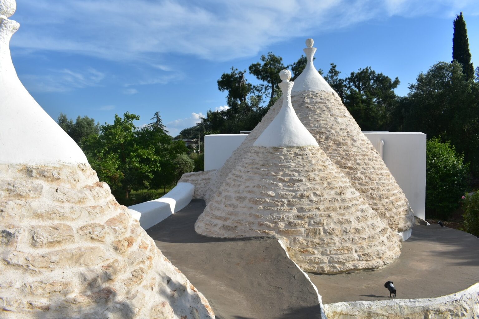 Trulli houses in Alberobello, Italy, showcasing their iconic conical roofs and stone construction against a clear blue sky. | Only on SopranoVillas