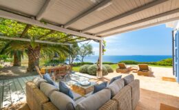 Luxurious outdoor living space with comfortable seating, a coffee table, and a stunning view of the ocean and greenery, ideal for relaxation and entertaining.