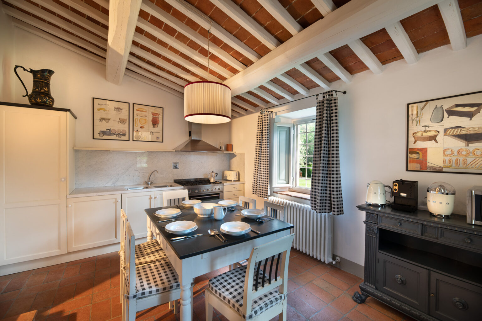 Modern kitchen interior with wooden beam ceiling, featuring a dining table set for six, stylish appliances, and decorative artwork on the walls. Natural light streams in through a window, enhancing the inviting atmosphere. | Only on SopranoVillas