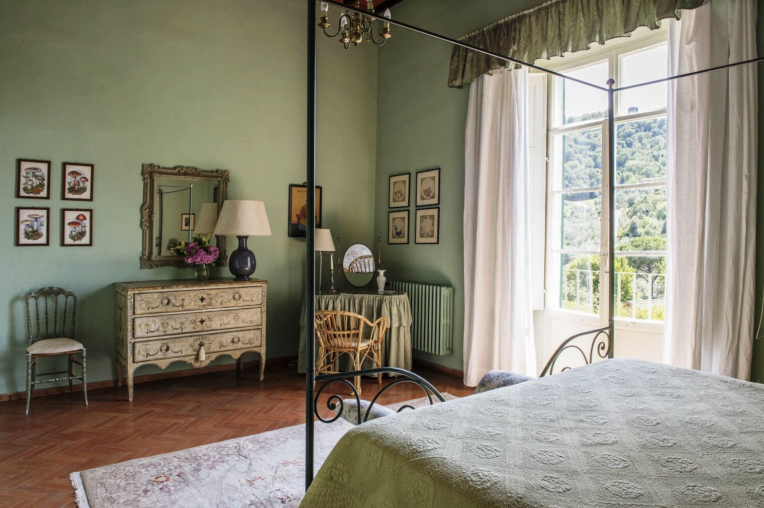 Cozy bedroom featuring green walls, large windows with scenic views, a vintage dresser, and elegant decor, creating a serene and inviting atmosphere. | Only on SopranoVillas